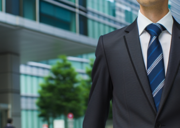 A man wearing business attire walking confidently towards an office building